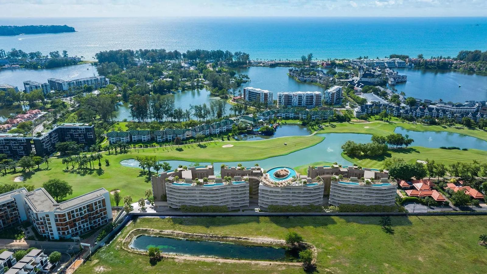 Angsana Golf Residences Topaz 在 Laguna Golf Phuket 之上的高空俯瞰,三幢弧形低座越過球道望向安達曼海