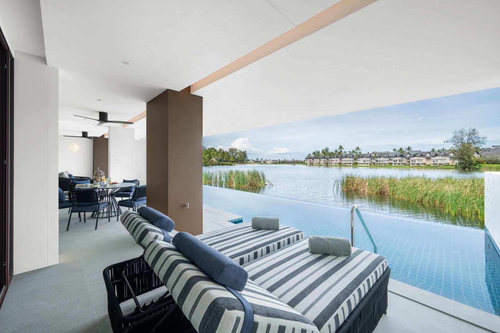 Photograph of the covered terrace of home 312, a finished two-bedroom in Building 3 at Angsana Oceanview Residences: a daybed beside the private pool, the lagoon beyond. October 2025