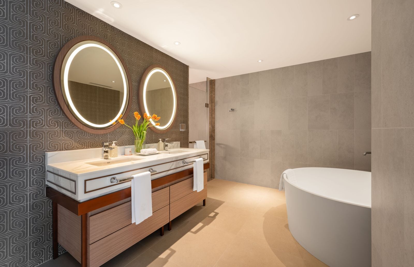 Photograph of the main bathroom of home 312, a finished two-bedroom in Building 3 at Angsana Oceanview Residences: a double vanity with round mirrors and a freestanding bathtub. October 2025