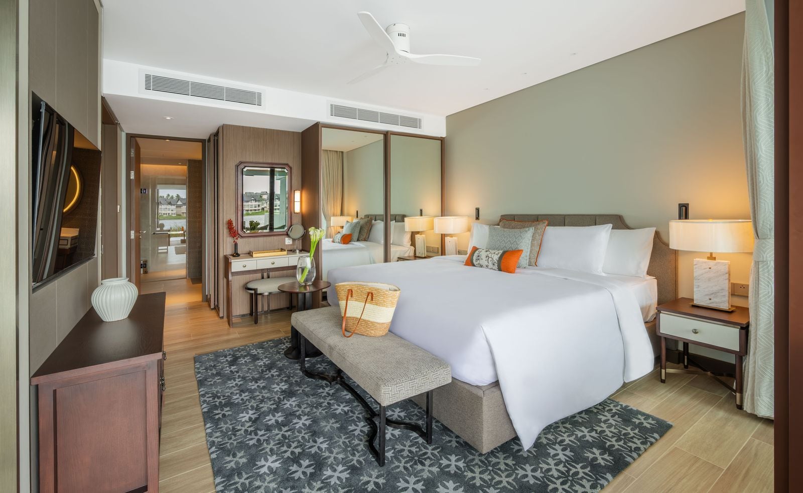 Photograph of the main bedroom of home 312, a finished two-bedroom in Building 3 at Angsana Oceanview Residences, furnished, with a dressing table and the walk-through to the bathroom. October 2025