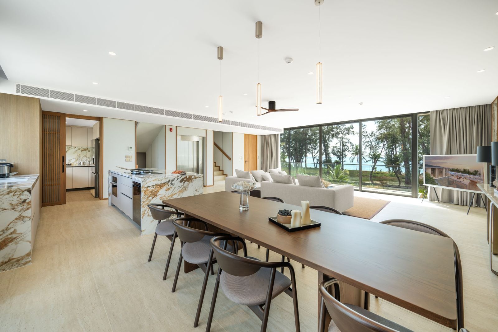 Banyan Tree Beach Residences Nammu 一個已完工聯排住宅廚房及餐檯的照片,攝於 2026 年 1 月:石材中島、備餐間,玻璃外是樹林