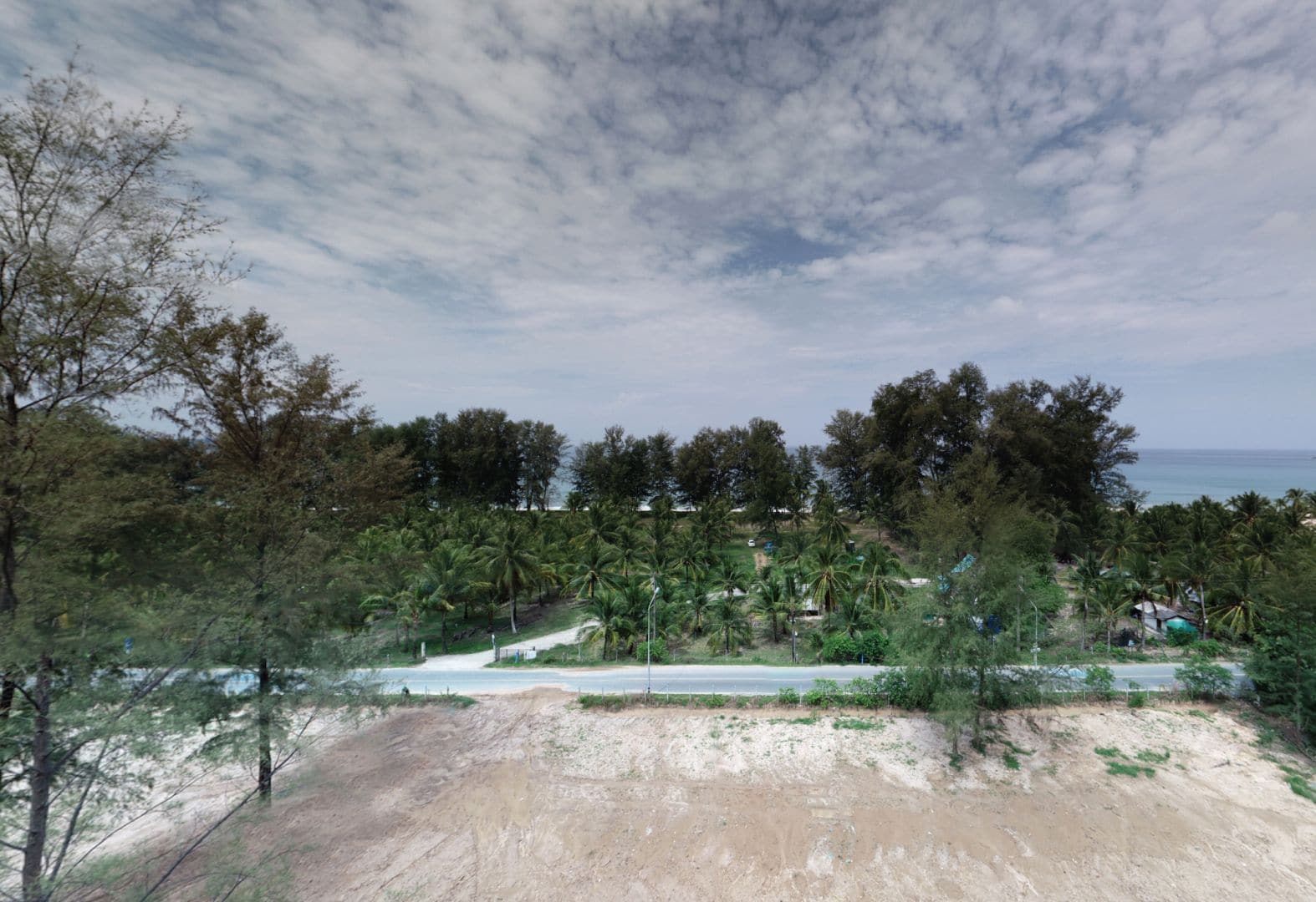 ภาพถ่ายของผู้พัฒนาแสดงวิวทางทิศตะวันตกจากระดับดาดฟ้าของ Banyan Tree Beach Residences Sirena: ที่ดินของ Aegir ที่เคลียร์แล้ว ถนนสาธารณะ สวนมะพร้าวที่มีอาคารเล็ก ๆ และทะเลที่อยู่ถัดไป