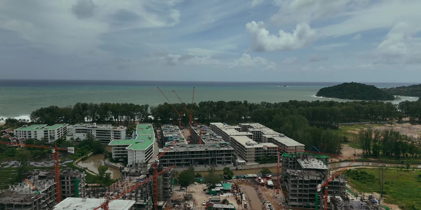 Eden Residences, Gardens of Eden, Phuket, under construction in August 2026, seen from a drone with the Andaman Sea and Bang Tao Bay behind