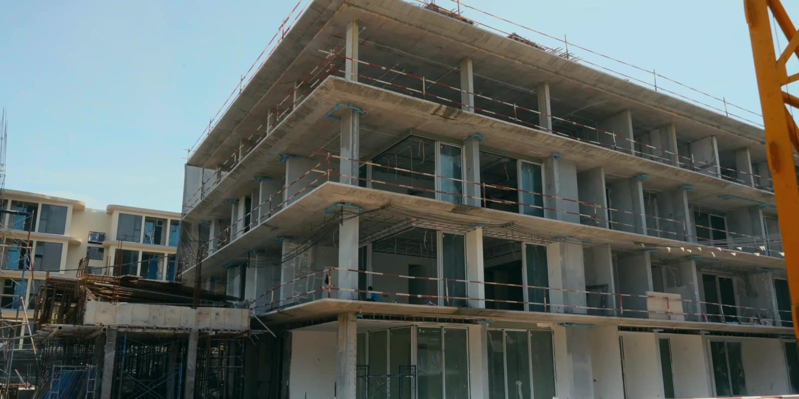 A four-storey building of Eden Residences, Gardens of Eden, Phuket, in August 2026, its frame complete and its windows going in