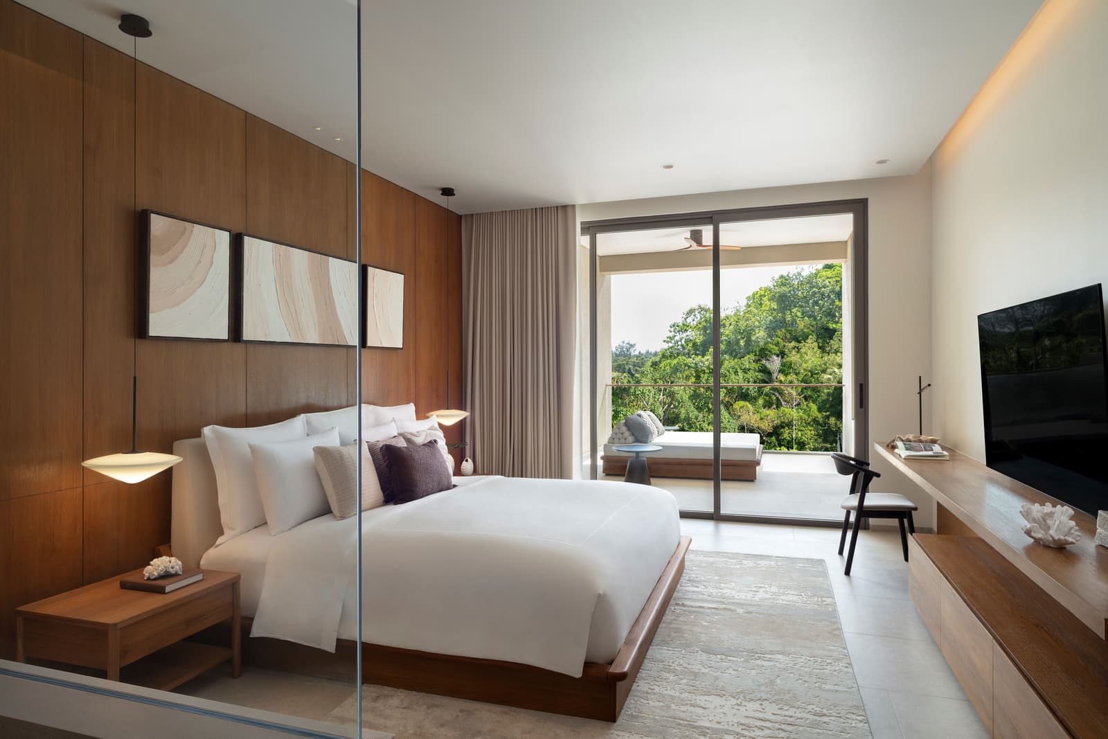 Master bedroom of the three-bedroom show condominium at Kiara Reserve Residences, Phuket, glass wall to the trees and a seating corner