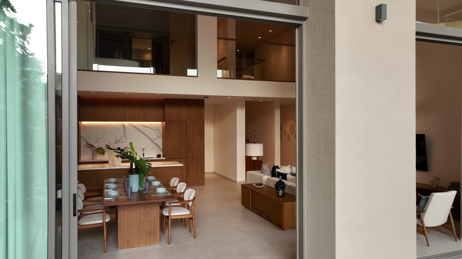 The double-height dining room and kitchen of the three-bedroom duplex show home at Kiara Reserve Residences, Phuket, the upper floor's gallery above