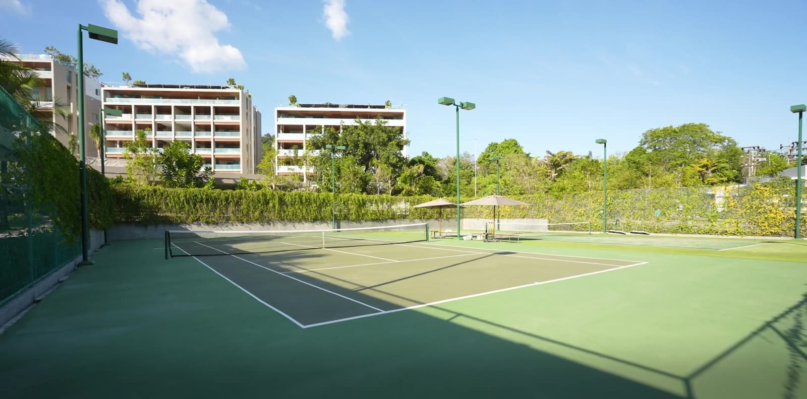 Теннисные корты Layan Active Zone под Kiara Reserve Residences, Пхукет, со зданиями поместья позади