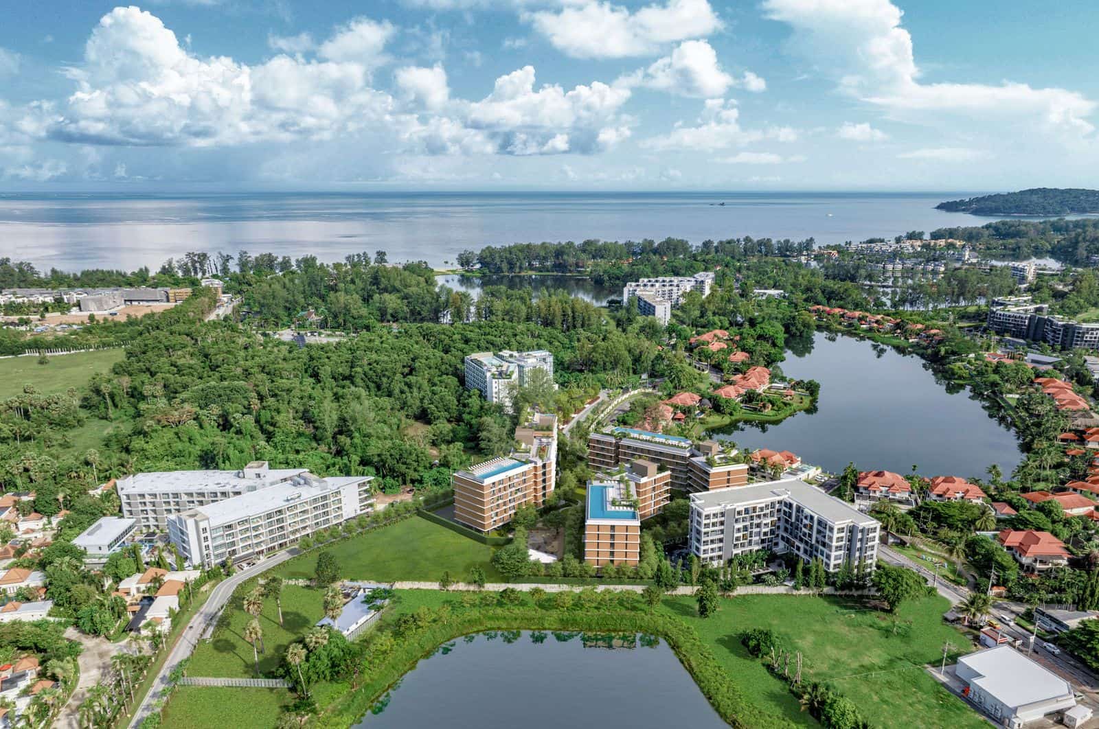 ภาพมุมสูงของ Laguna Lake Residences Aster ริมทะเลสาบใน Laguna Phuket มีทะเลอยู่สุดขอบฟ้า: ภาพถ่ายโดรนของผู้พัฒนาที่ใส่อาคารเป็นภาพจำลอง