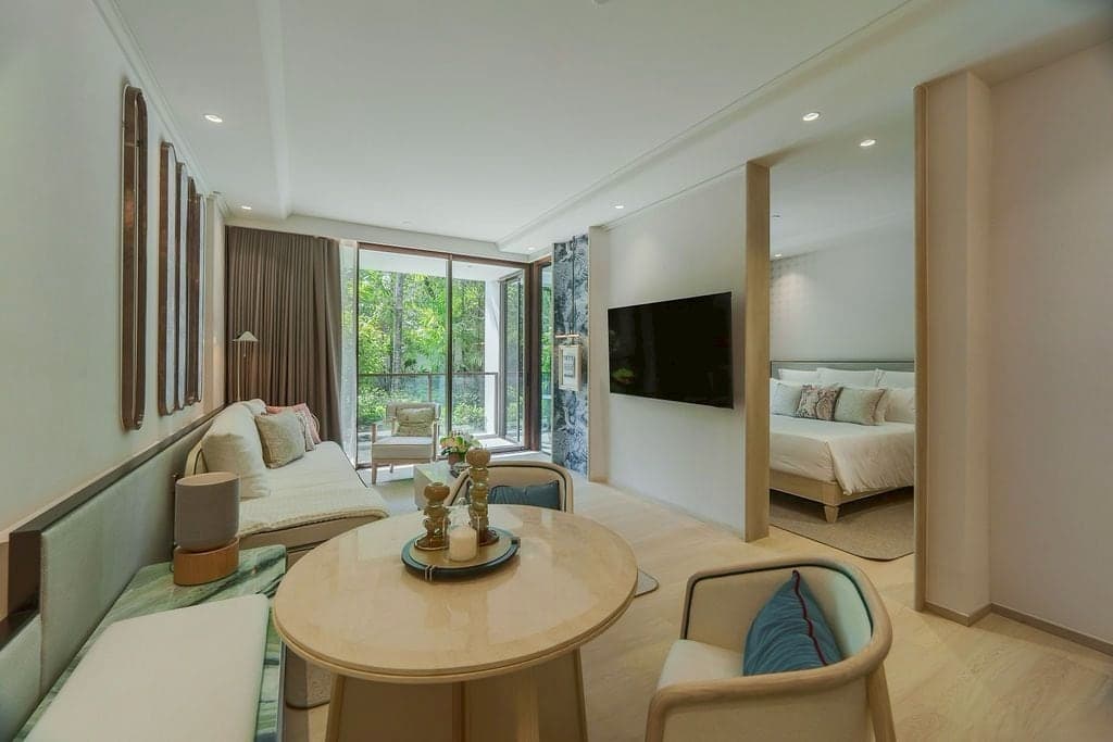 Living and dining room of the furnished one-bedroom show unit, 67 sqm, of The Residences at InterContinental Phuket Resort at PROUD's sales gallery, full-height windows onto a garden