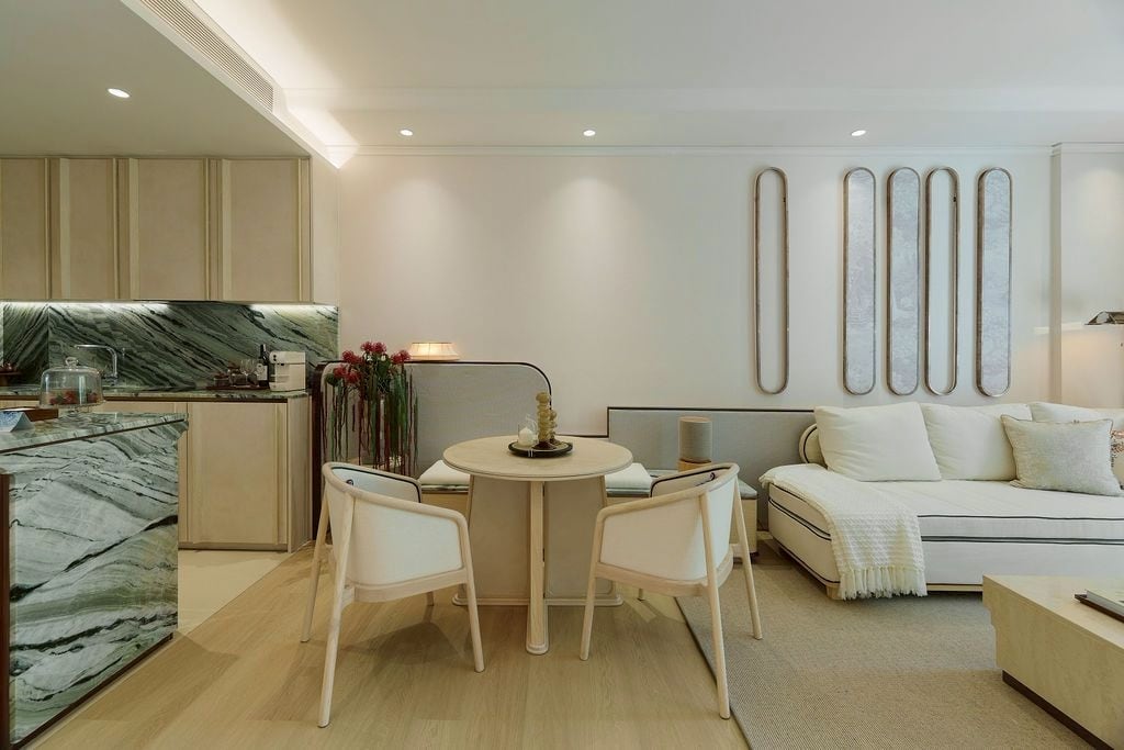 Open kitchen, dining table and sofa in the furnished one-bedroom show unit of The Residences at InterContinental Phuket Resort, with a green jade-marble island