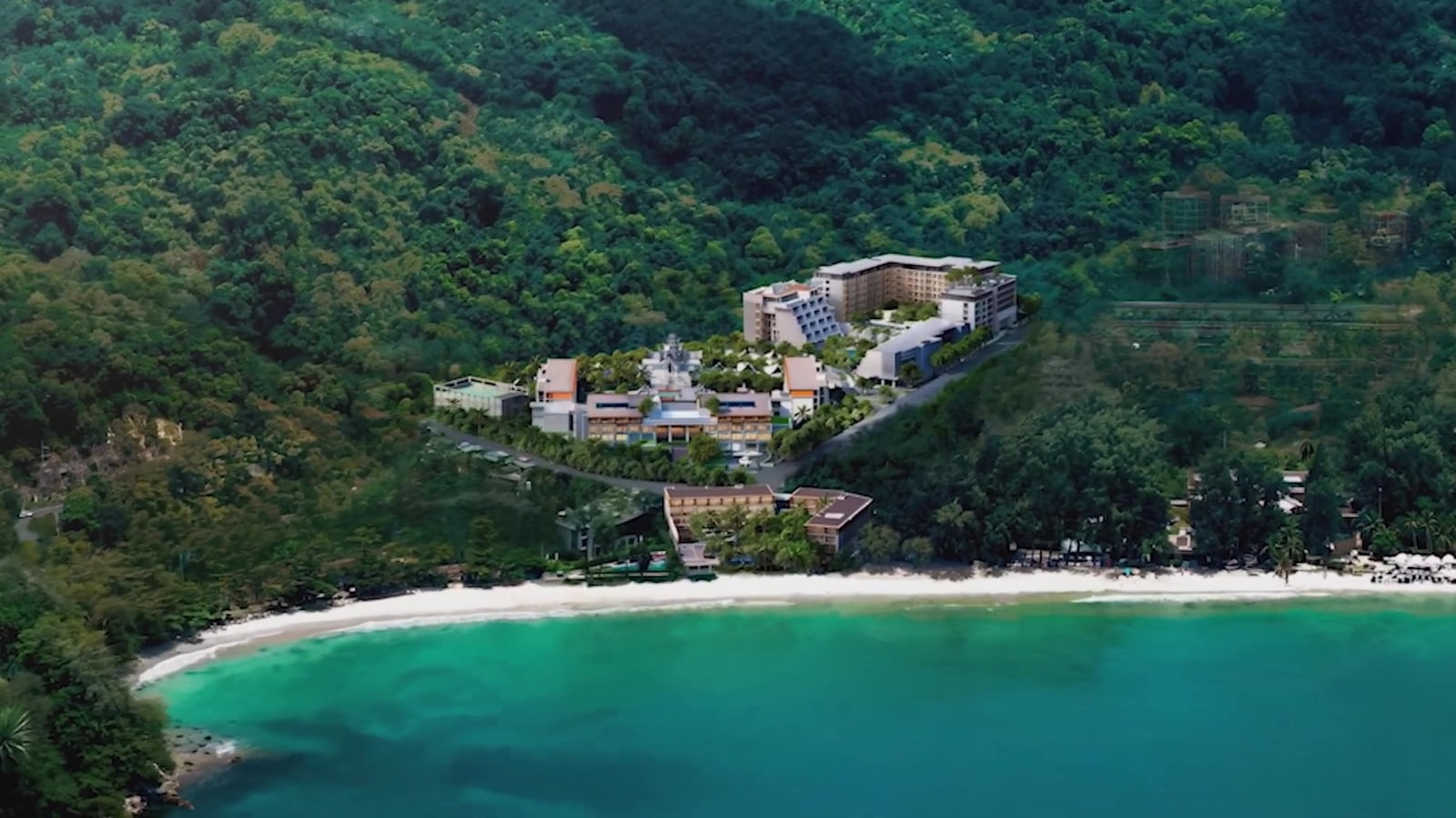ภาพมุมสูงของ InterContinental Phuket Resort เหนือหาด Kamala โดยวาดอาคารพักอาศัยสองหลังของ The Residences at InterContinental Phuket Resort ไว้บนเนินเขาด้านหลัง