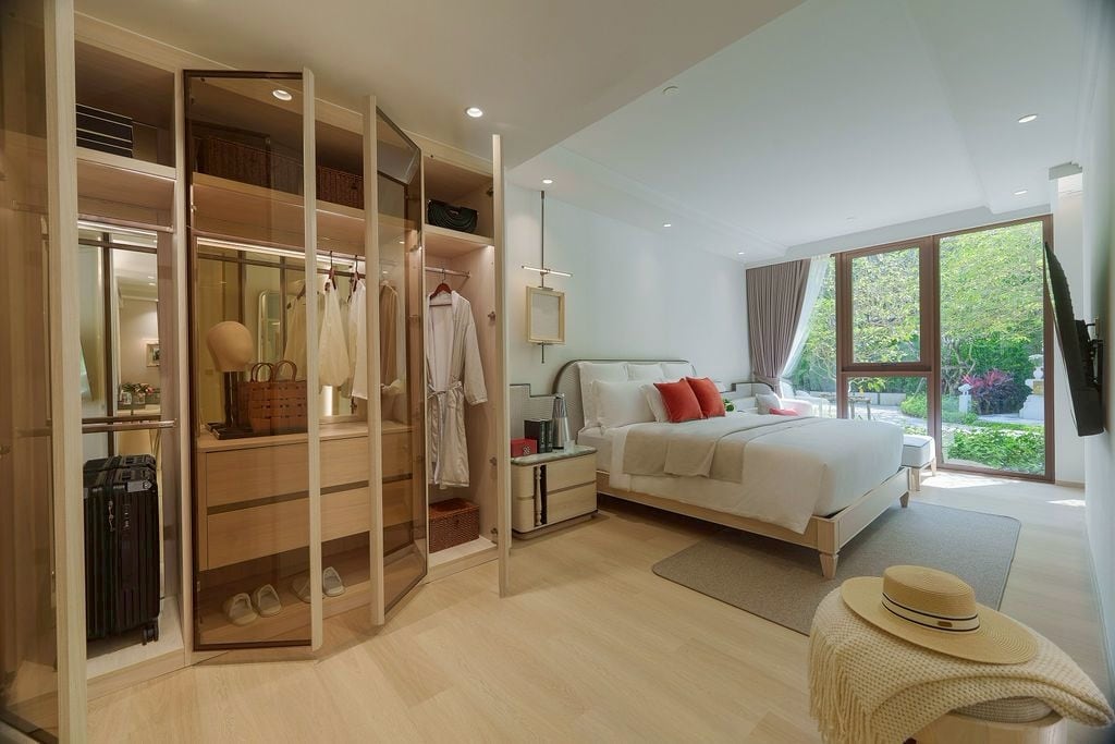 ห้องนอนใหญ่ของห้องตัวอย่าง 2 ห้องนอนของ The Residences at InterContinental Phuket Resort ตู้เสื้อผ้าแบบวอล์กอินหน้ากระจก และหน้าต่างมองออกสู่สวน