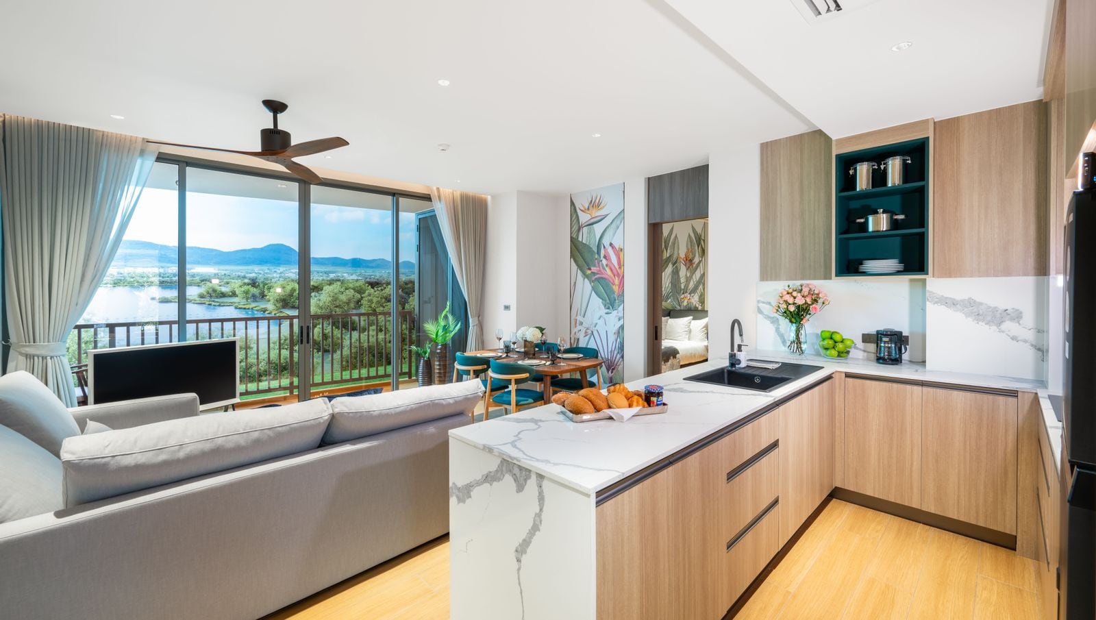 Photograph of the living room and kitchen of the Skypark Elara Lakelands Phuket show unit, the lake through the window