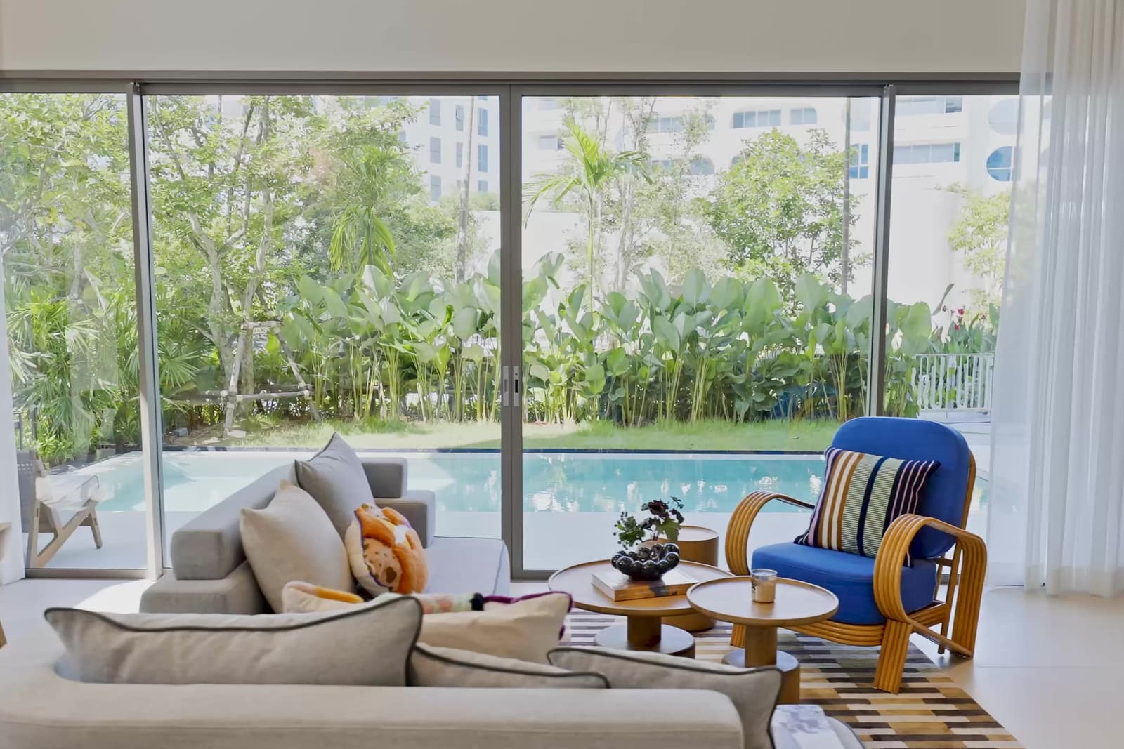 ห้องนั่งเล่นของดูเพล็กซ์ตัวอย่างที่ The Standard Residences, Phuket Bang Tao ประตูกระจกเปิดออกสู่สระส่วนตัวและสวน