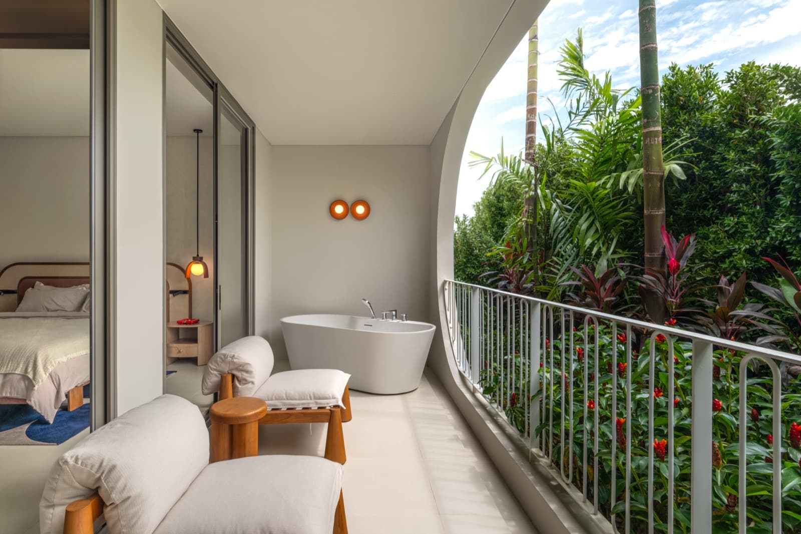 อ่างอาบน้ำบนระเบียงของห้องตัวอย่าง 1 ห้องนอนที่ The Standard Residences, Phuket Bang Tao ข้างเก้าอี้พักผ่อน และสวนต้นปาล์ม