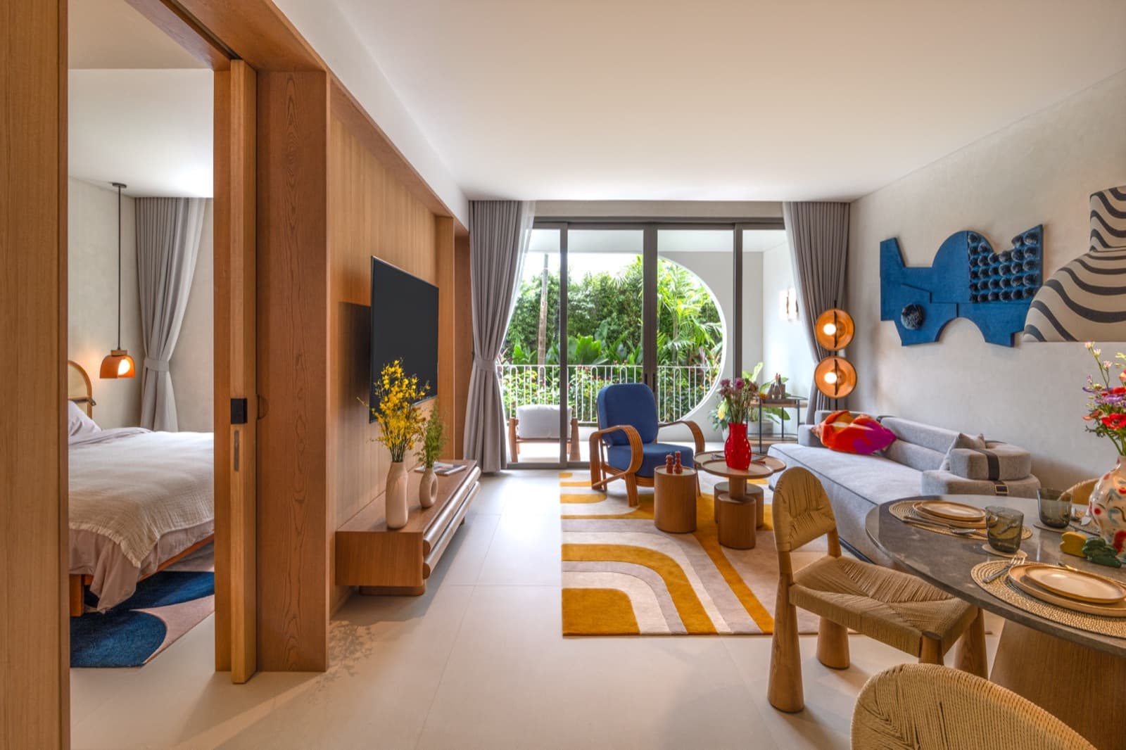 ห้องนั่งเล่นของห้องตัวอย่าง 1 ห้องนอนที่ The Standard Residences, Phuket Bang Tao เปิดต่อเนื่องกับห้องนอน พร้อมหน้าต่างทรงกลมและวิวสวน