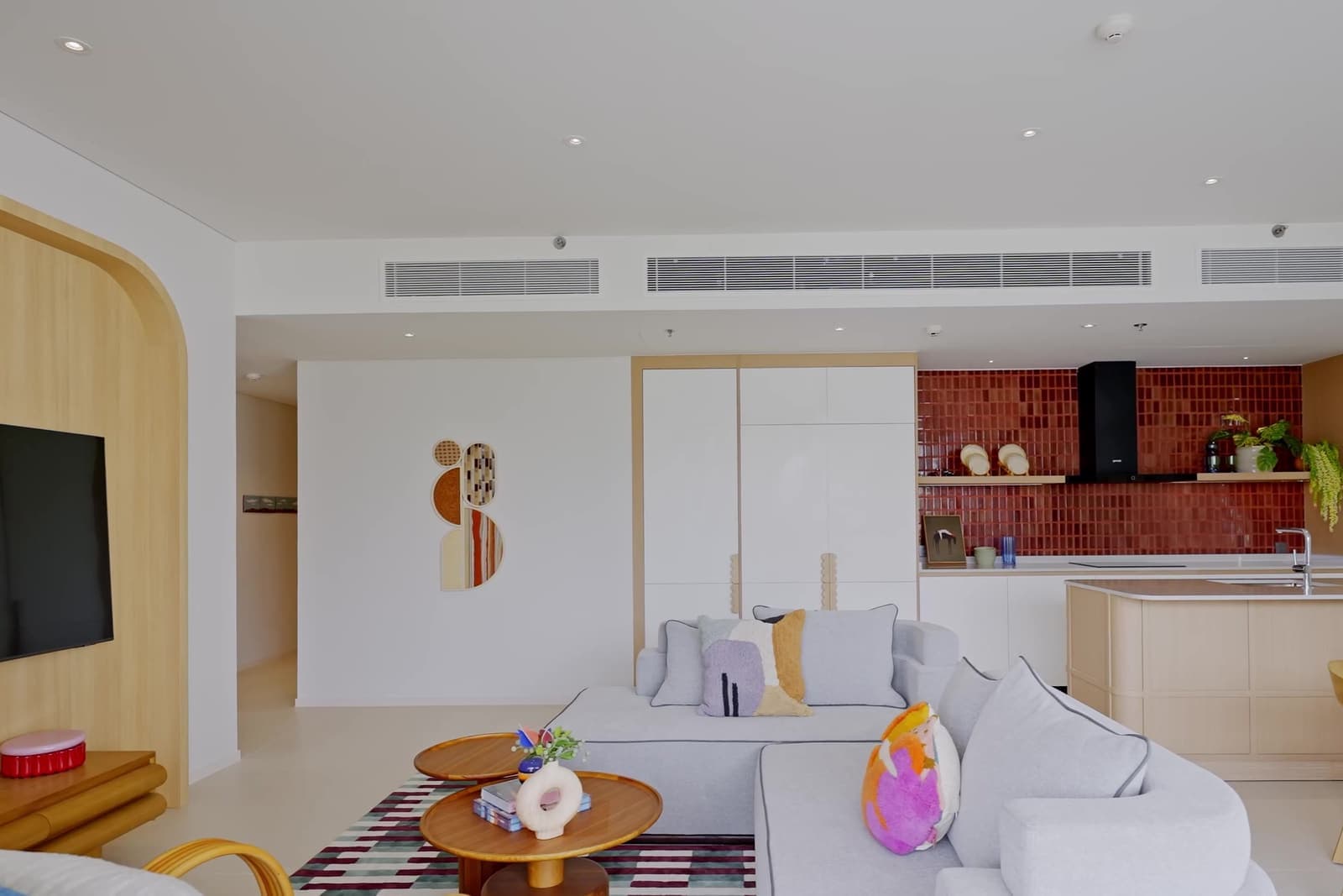 ห้องนั่งเล่นและครัวเปิดของห้องตัวอย่าง 3 ห้องนอนที่ The Standard Residences, Phuket Bang Tao พร้อมกระเบื้องสีแดงด้านหลังครัว