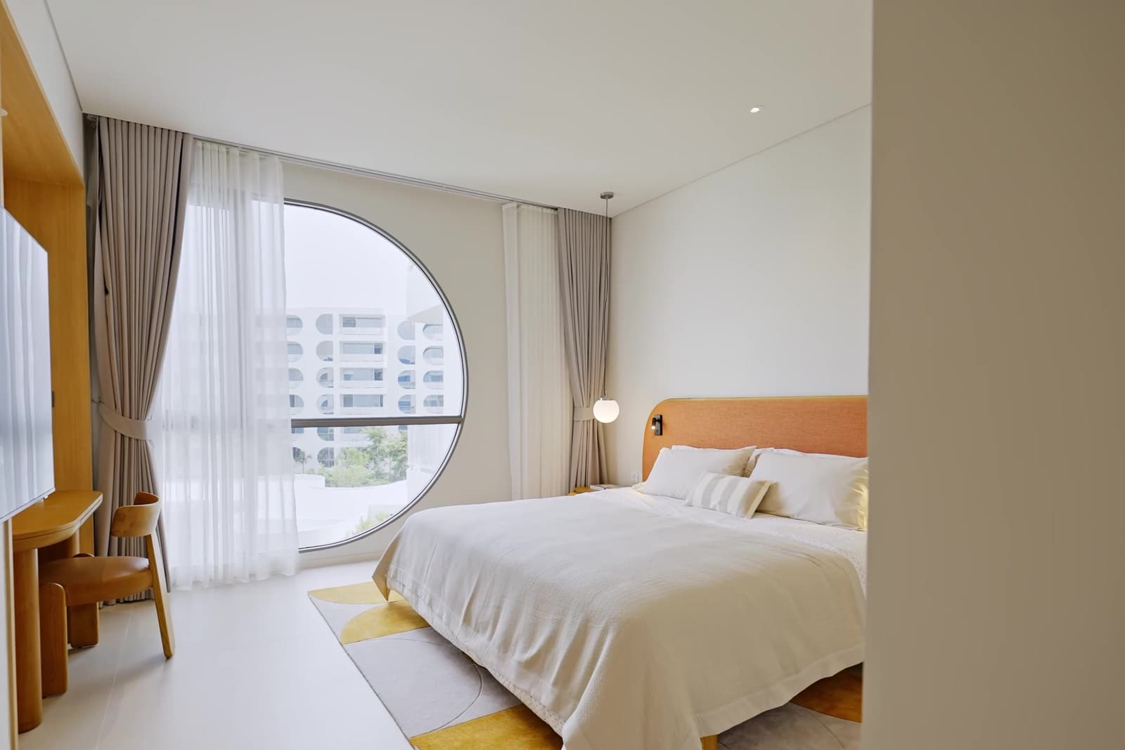 ห้องนอนใหญ่ของห้องตัวอย่าง 3 ห้องนอนที่ The Standard Residences, Phuket Bang Tao พร้อมหน้าต่างทรงกลมบานใหญ่