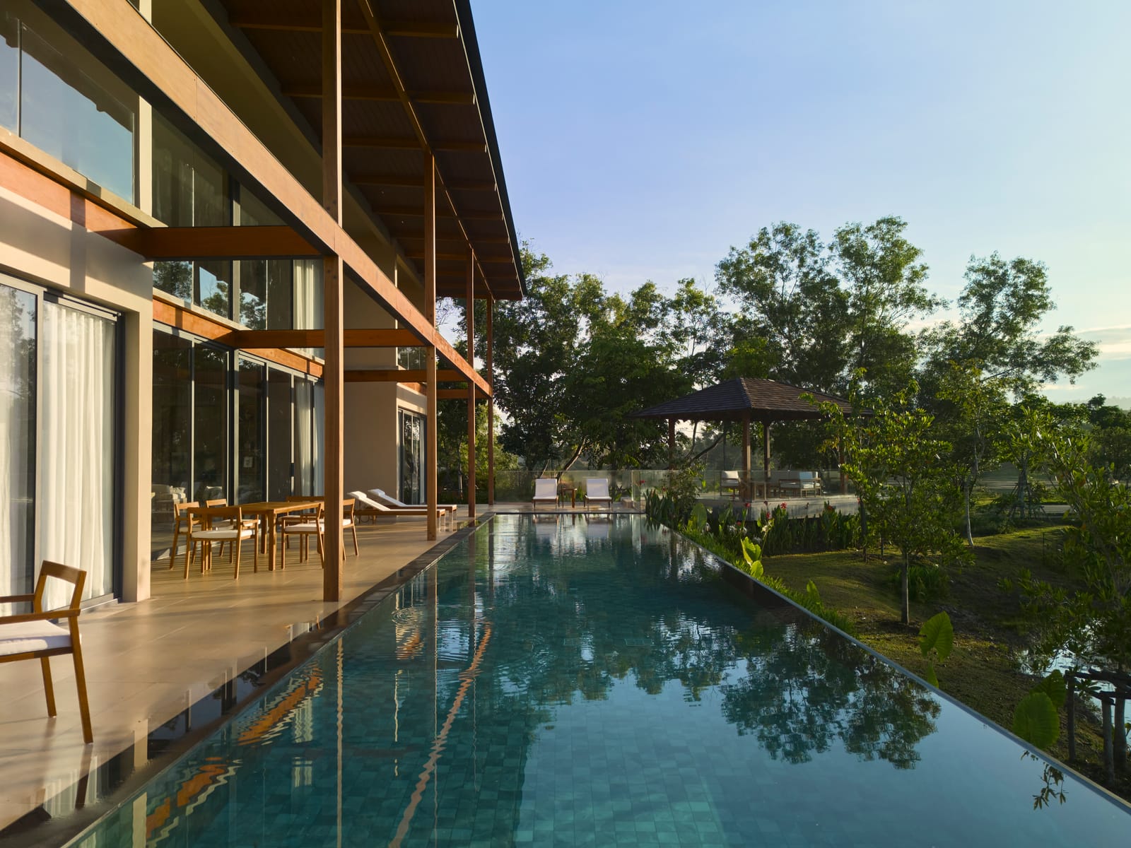 The pool terrace of the Vana 4 show villa at Tri Vananda, Phuket, the pool edge running out towards the lake
