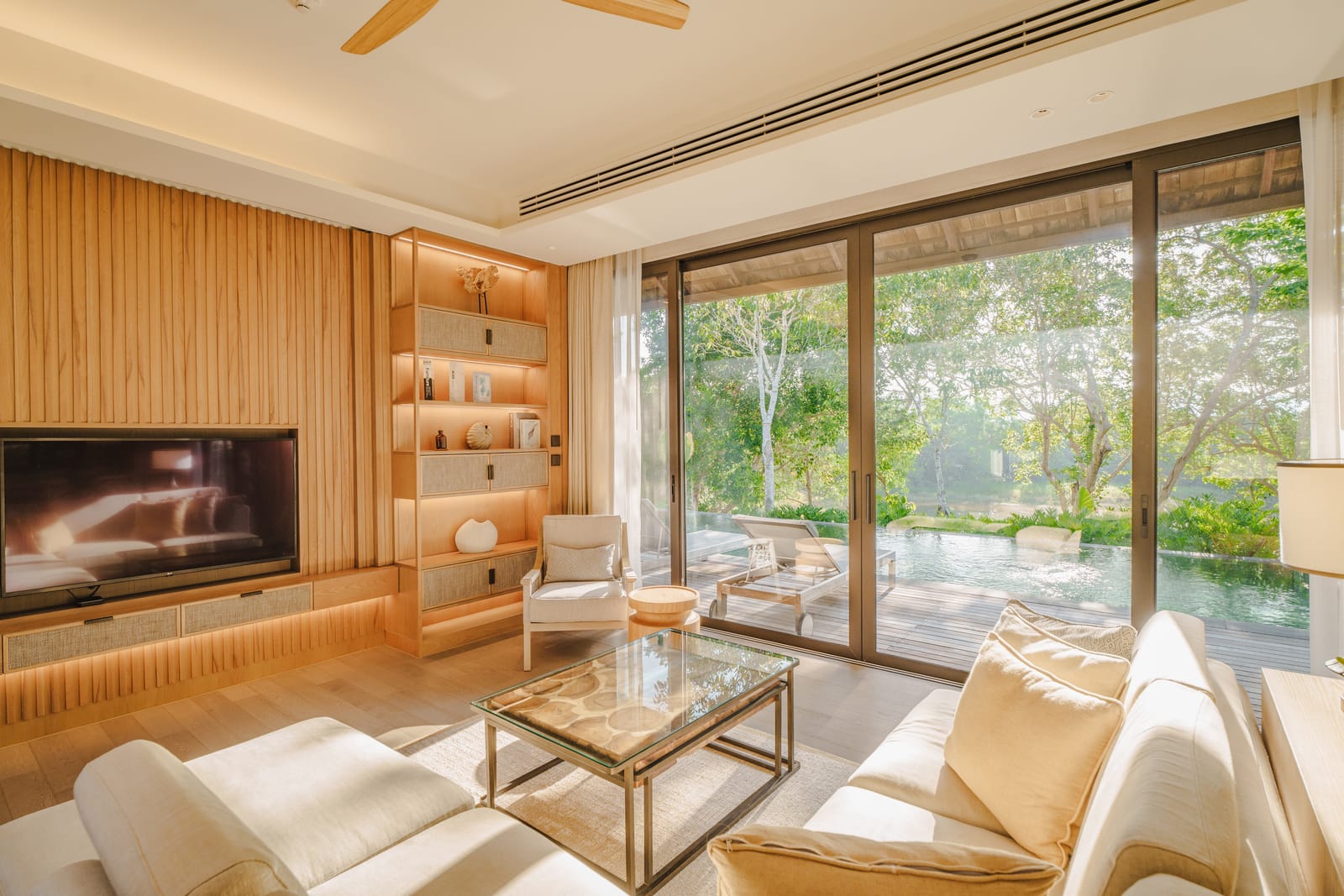 The living room of a finished Vana 3 wooden villa at Tri Vananda, Phuket, in oak with sliding glass to the pool