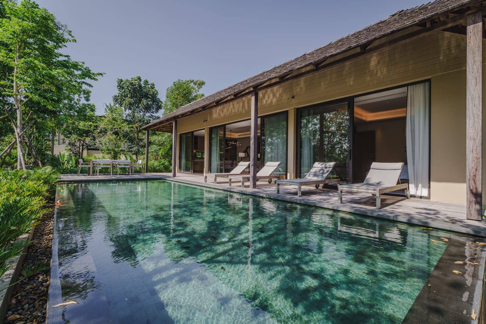 The pool and terrace of a finished Vana 3 wooden villa at Tri Vananda, Phuket, forest around it