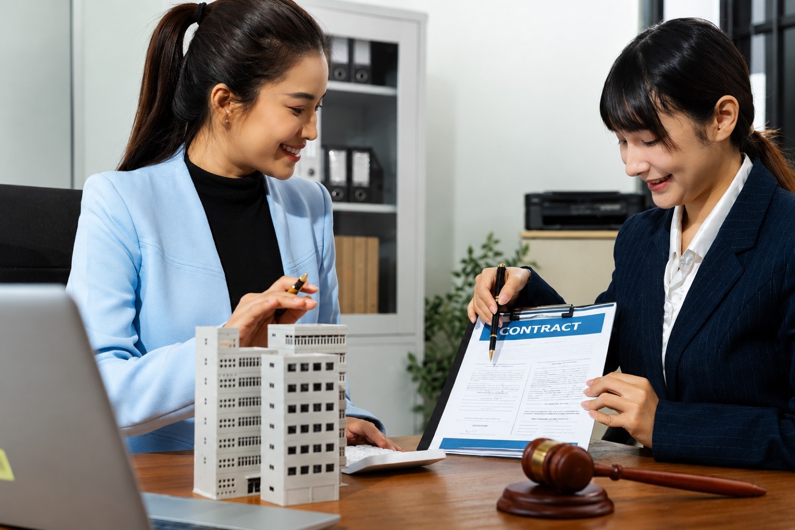 律師在書桌前審閱一份泰國物業合約,手持鋼筆停在簽署頁上