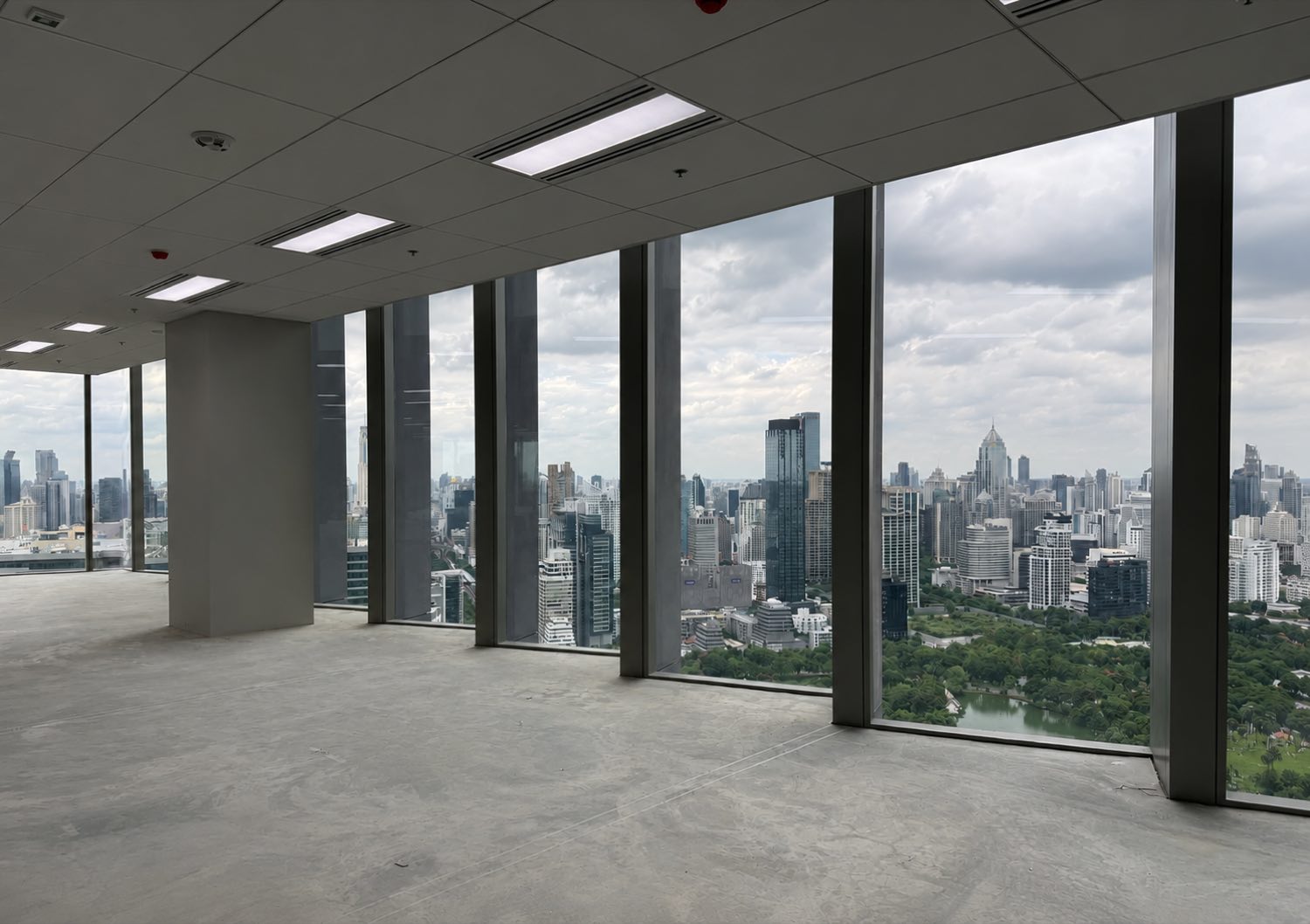 Dusit Central Park 综合项目内一层未经装修的高层办公室,落地玻璃俯瞰曼谷市中心与 Lumphini Park