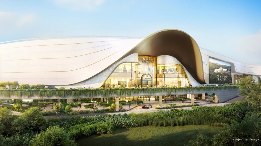 Central Pattana 的效果图:Phuket Wichit 扩建后的 Central Phuket Floresta,弧形金色调外墙与玻璃入口,前方是热带植物