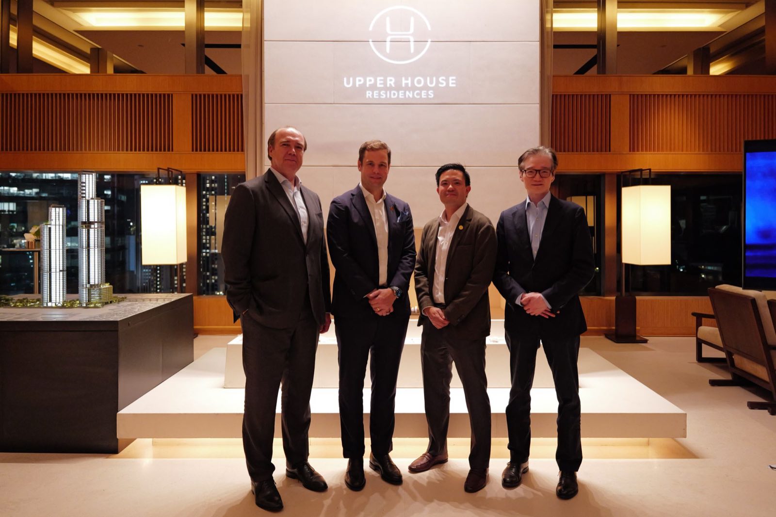 City Realty 與 Swire 的四位管理層,立於 Upper House Residences 品牌牆與亮起的大樓模型之前