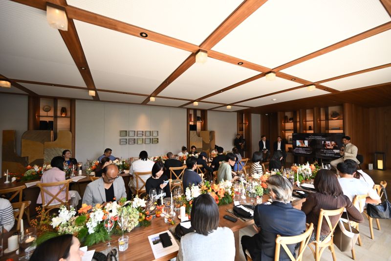 Guests seated at long tables with white flowers under a timber-beamed ceiling during the Upper House Residences Bangkok presentation