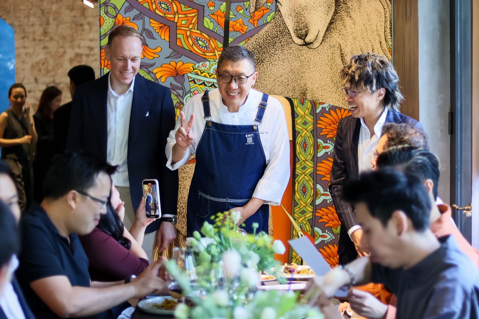 客席廚師在 Upper House Residences Bangkok 推出晚宴上迎接賓客,身後是一幅色彩鮮明的壁畫