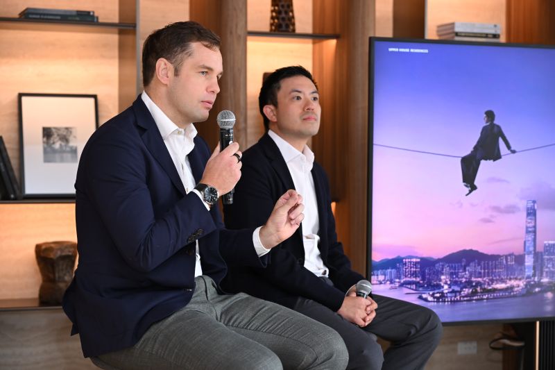 A speaker talks about Upper House Residences Bangkok, with an image of the Hong Kong harbour skyline on the screen behind