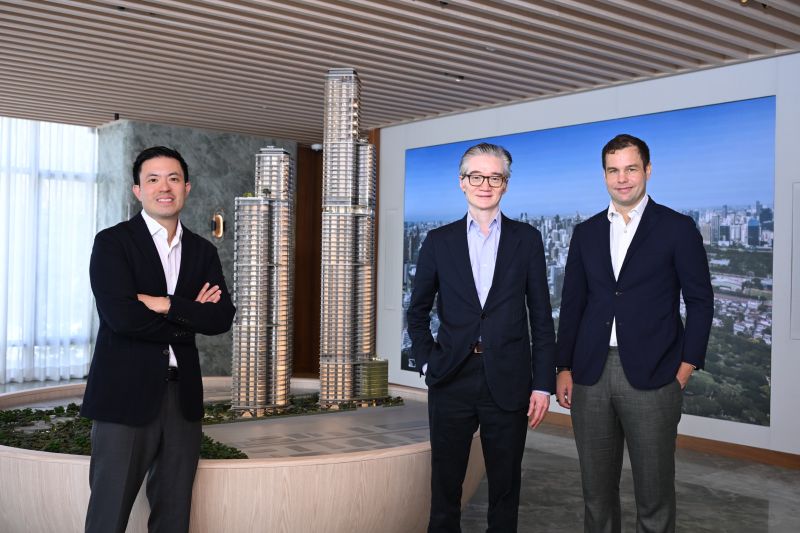 Three members of the Upper House Residences team stand beside the scale model of Upper House Residences Bangkok and The Wireless Residences by Upper House, with a photograph of the Bangkok skyline and Lumphini Park behind them