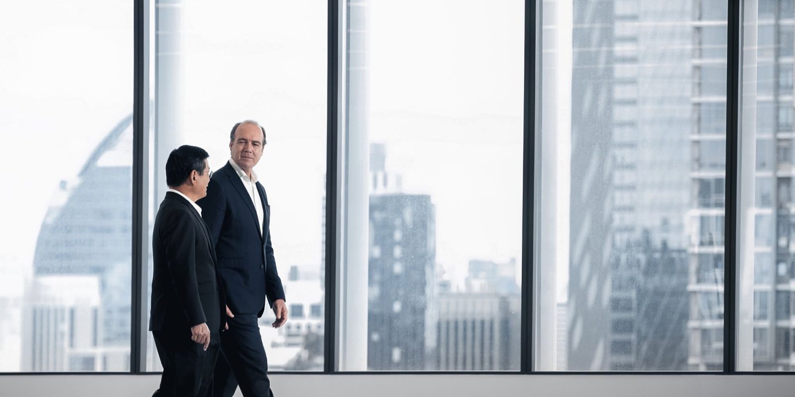City Realty 與 Swire Properties 的兩位管理層,走過一層空置的高層樓面,下方是曼谷市中心的天際線;取自 City Dynamic 的 Upper House Residences 幕後片段