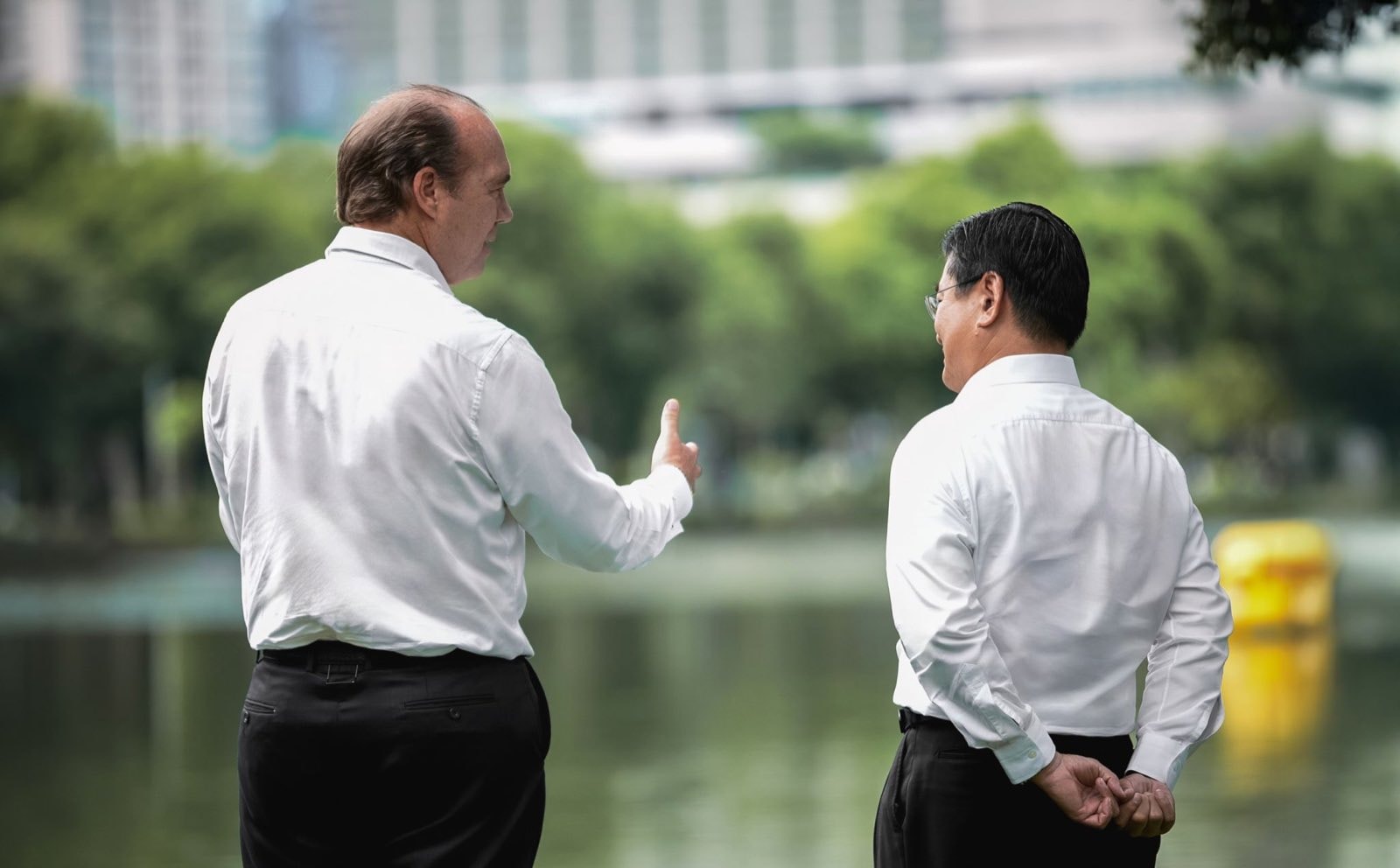 City Realty 与 Swire 的两位管理层背向镜头,在曼谷市中心一座公园的湖畔交谈