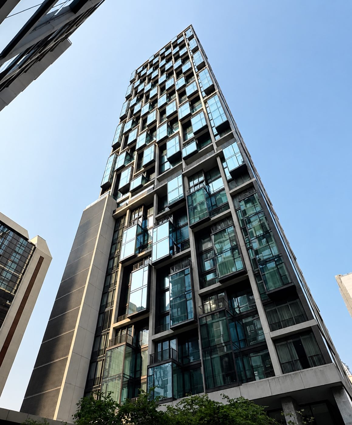 The 28 Chidlom tower rising overhead, its stacked glass bays seen from the street on Soi Chidlom in central Bangkok