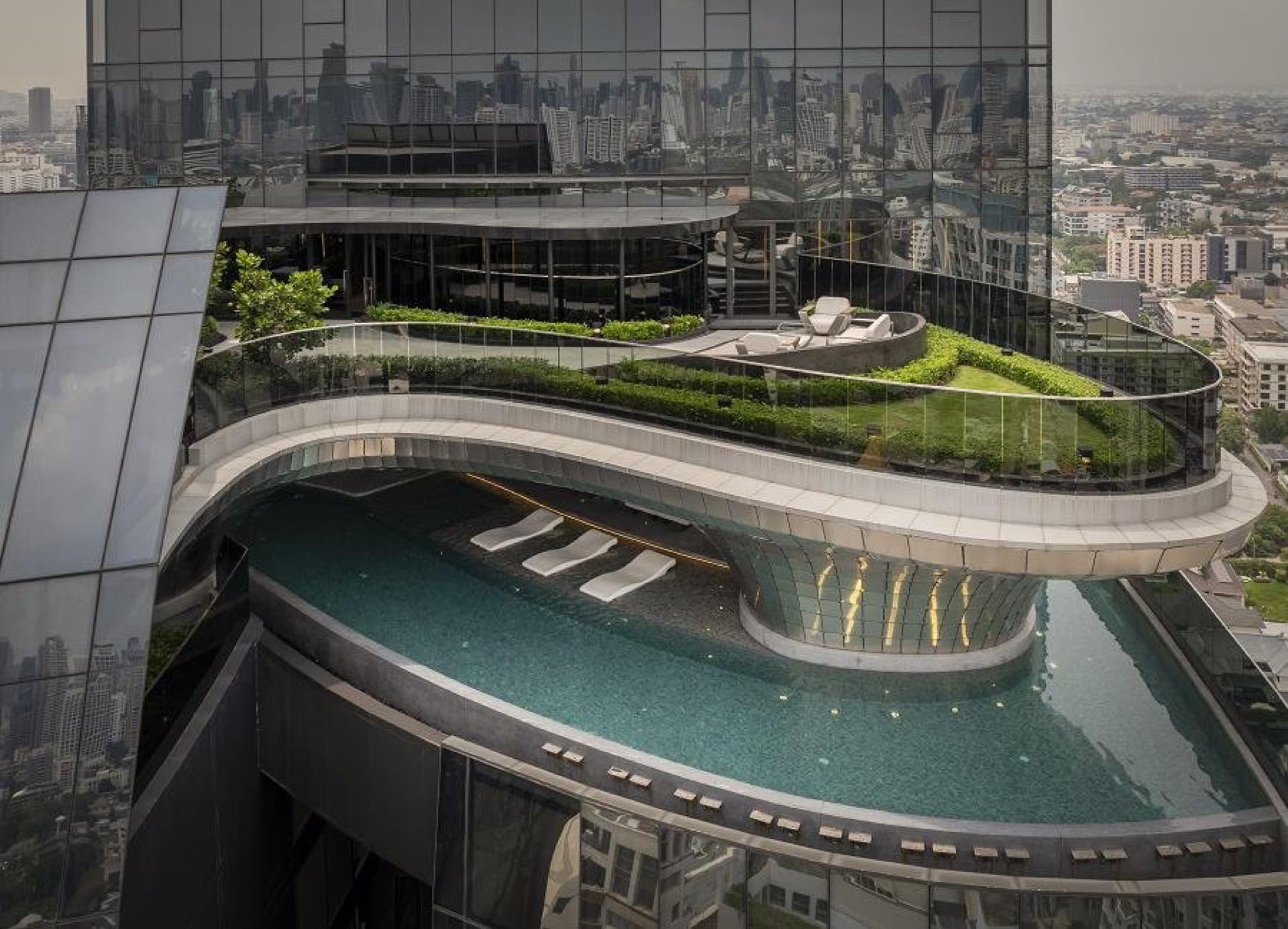 AESTIQ Thonglor: Rooftop sky garden and curved infinity pool of AESTIQ Thonglor with the Bangkok skyline behind