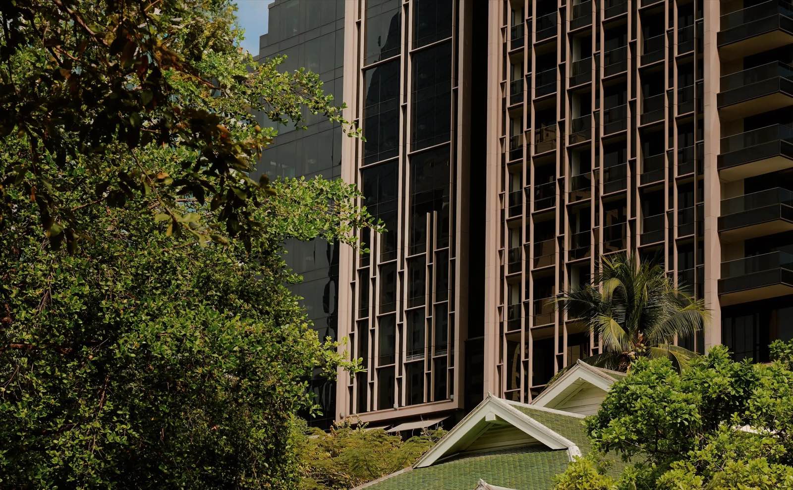 Aman Nai Lert Residences อาคาร Aman Nai Lert Bangkok ตั้งตระหง่านเหนือสวนอันเก่าแก่ แสดงฟาซาดแนวตั้งโทนสีบรอนซ์