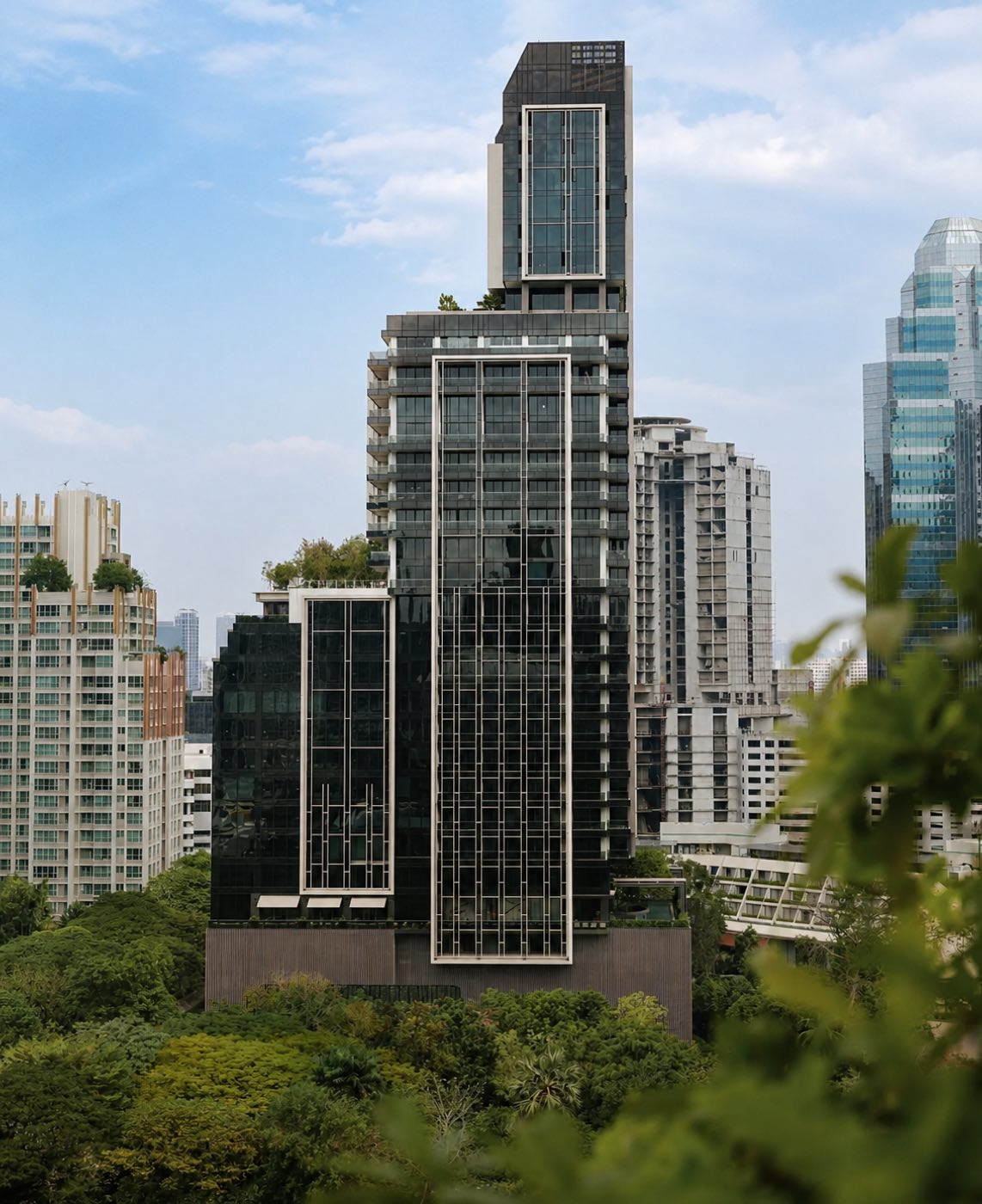 Aman Nai Lert Residences: the bronze-and-glass residential tower rising above the mature trees of the historic Nai Lert estate in central Bangkok