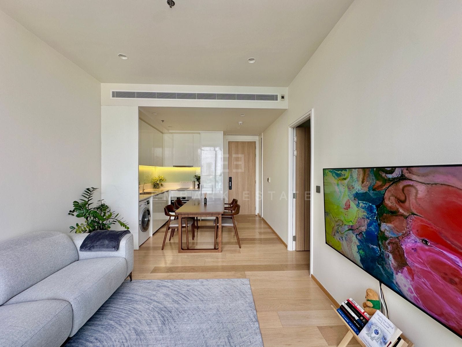 The living and dining room of a 1-bedroom residence at ANIL Sathorn 12, Bangkok, with a large abstract artwork above the media wall
