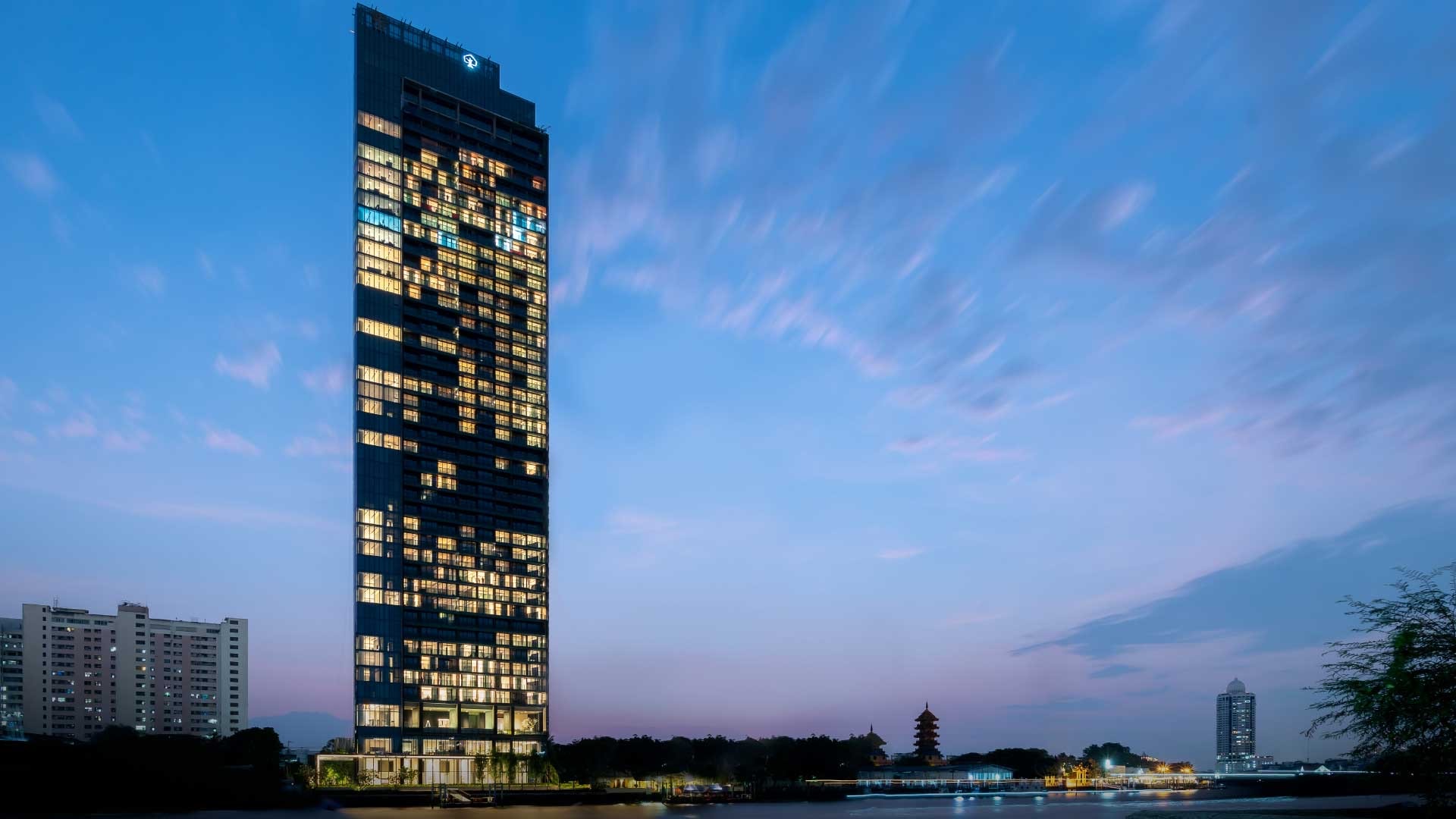 Banyan Tree Residences Riverside Bangkok: full riverside tower exterior illuminated at dusk on the Chao Phraya River