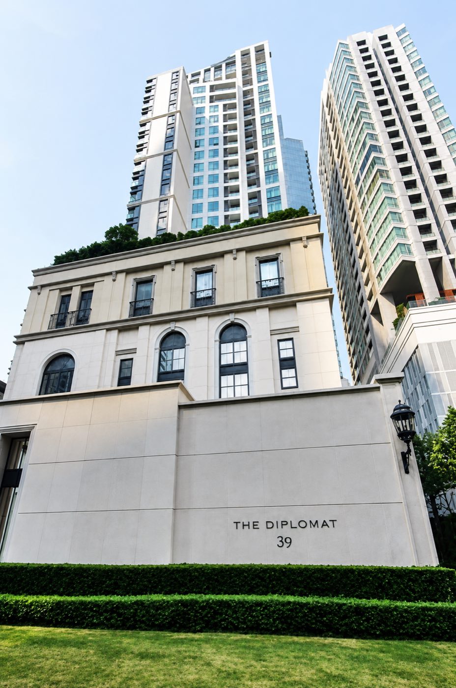 The Diplomat 39: the classical stone arrival pavilion with the THE DIPLOMAT 39 signage and the residential tower rising above, on Sukhumvit 39 in Bangkok