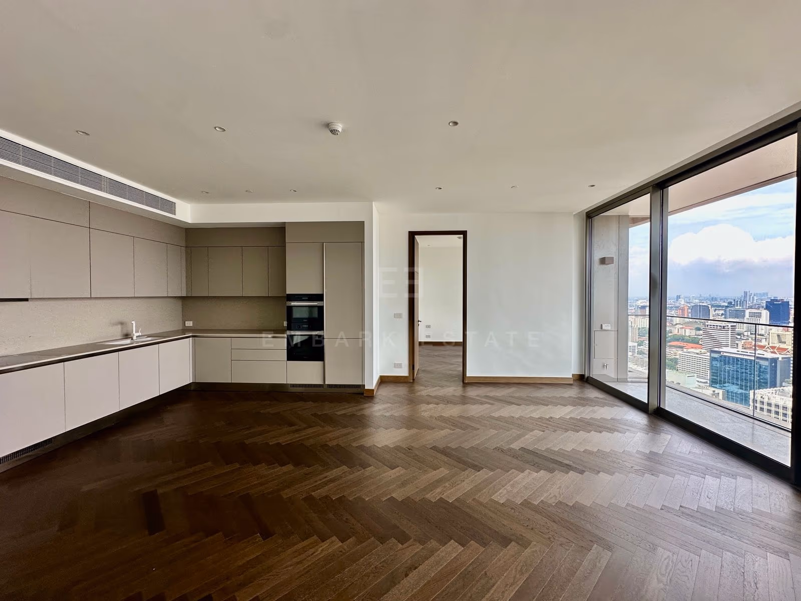ครัวและห้องนั่งเล่นของยูนิต 3202 ที่ Dusit Residences, Dusit Central Park ด้านหนึ่งเป็นกระจกระเบียง และมีประตูห้องนอนอยู่ถัดไป