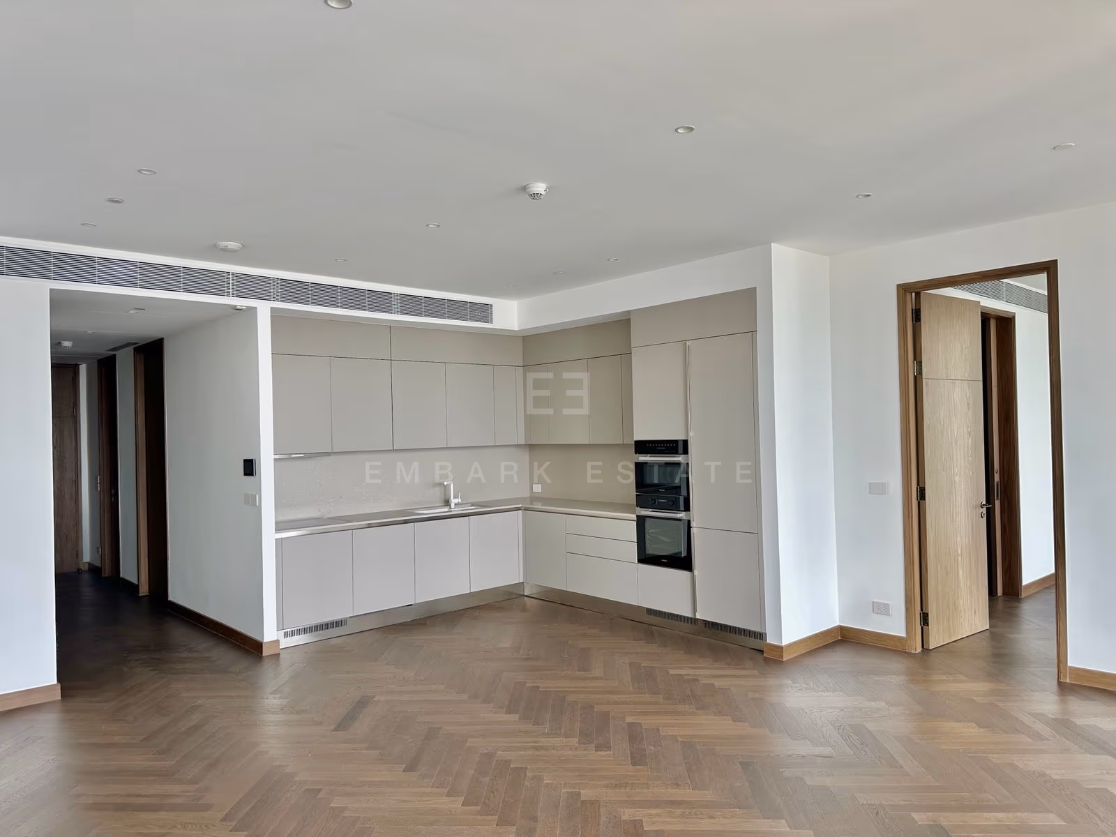 The kitchen of unit 3202 at Dusit Residences, Dusit Central Park, pale handle-less cabinetry set in an L with built-in Miele ovens and a tall integrated fridge