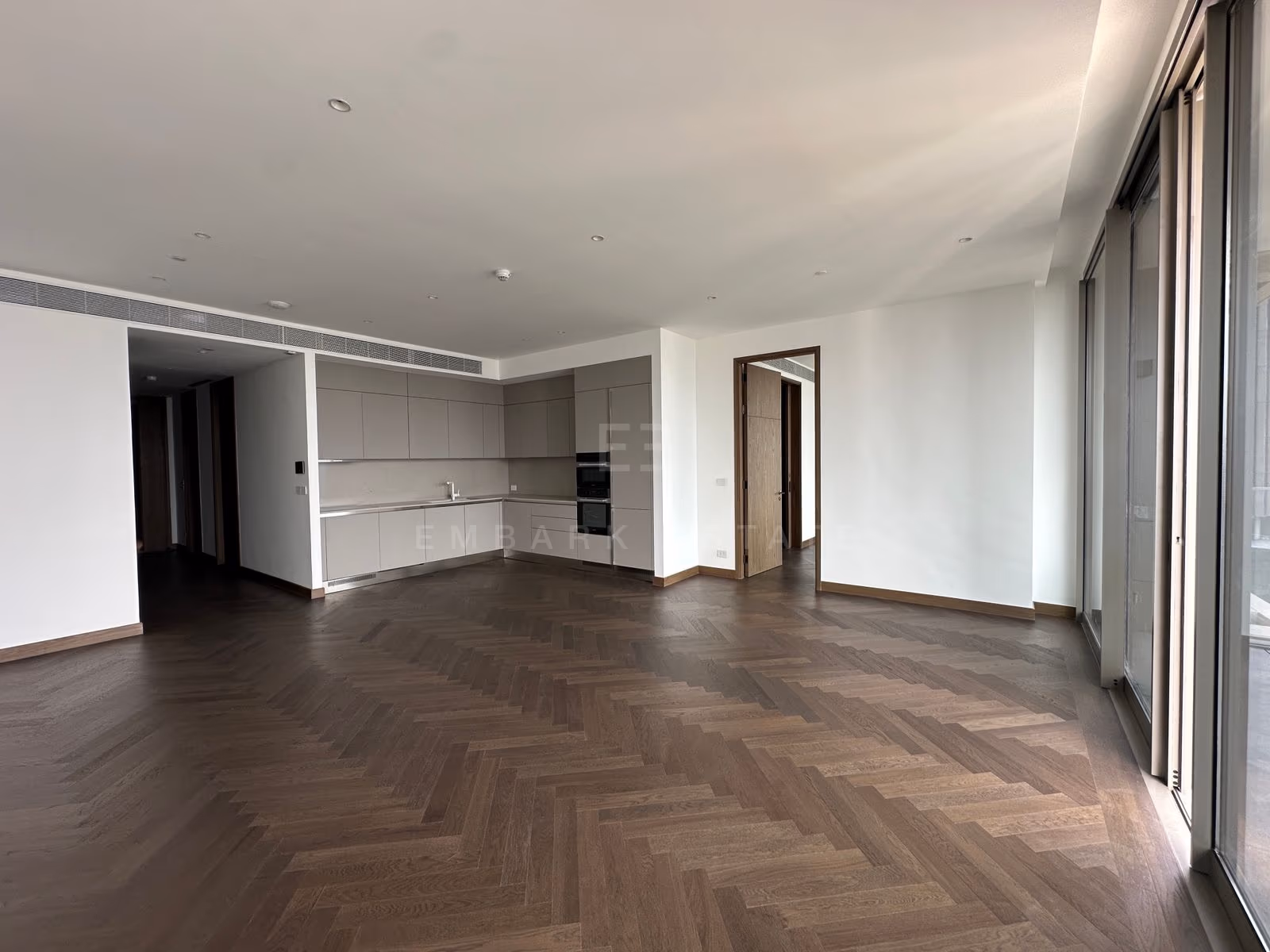 พื้นที่นั่งเล่น รับประทานอาหาร และครัวแบบเปิดของยูนิต 3202 ที่ Dusit Residences, Dusit Central Park บนพื้นไม้โอ๊กลายก้างปลา โดยมีโถงทางเข้าอยู่ทางซ้าย