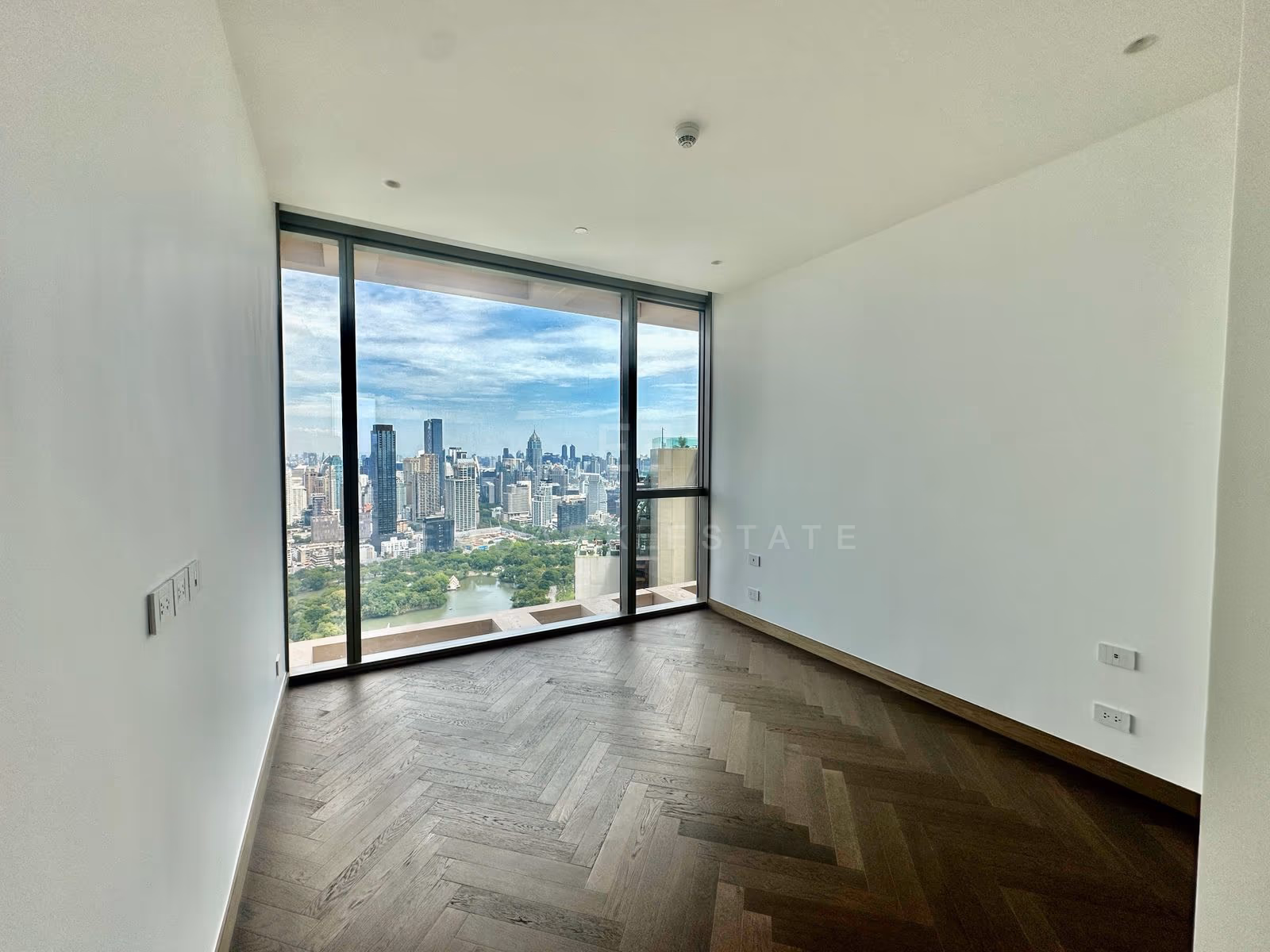 A bedroom of unit 3903 at Dusit Residences, Dusit Central Park, framing the lake of Lumphini Park through floor-to-ceiling glass