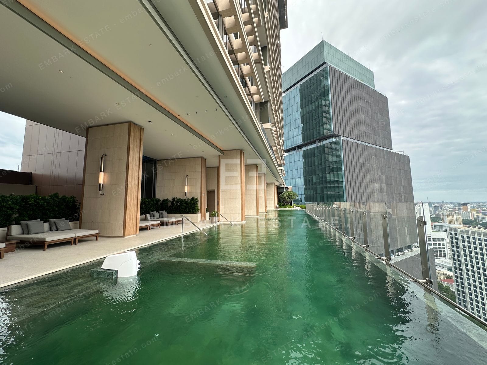The rooftop infinity pool at Dusit Central Park, its green water meeting the central Bangkok skyline, home to Dusit Residences on Rama IV Road