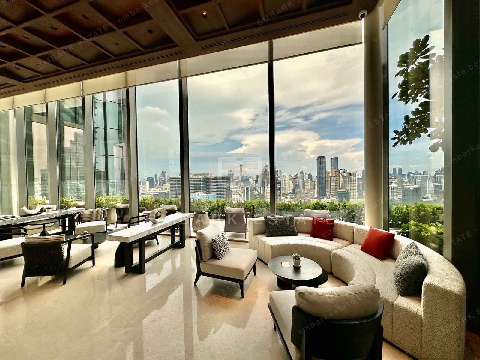 A residents' lounge at Dusit Central Park with a curved sofa and floor-to-ceiling windows over the central Bangkok skyline, home to Dusit Residences and Dusit Parkside on Rama IV Road