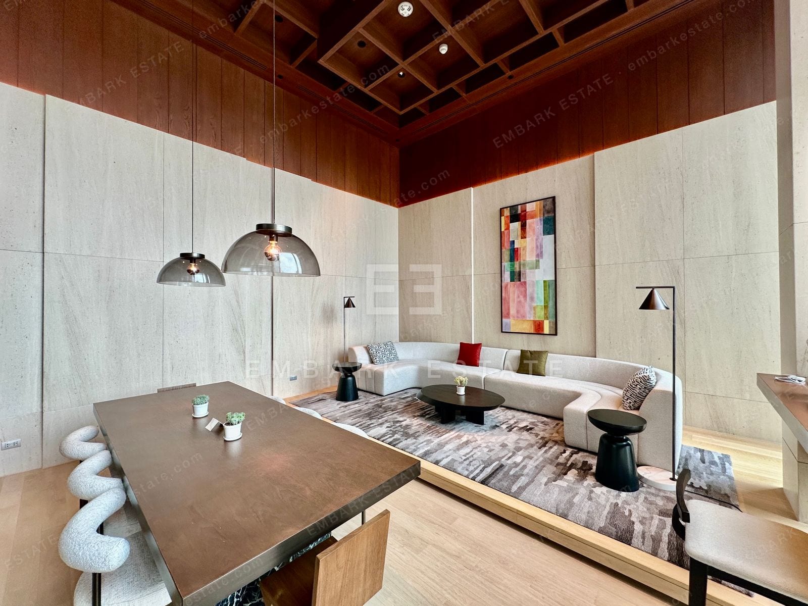 A residents' lounge and dining room at Dusit Central Park with a long dining table, a curved sofa and a coffered timber ceiling, home to Dusit Residences and Dusit Parkside on Rama IV Road in central Bangkok