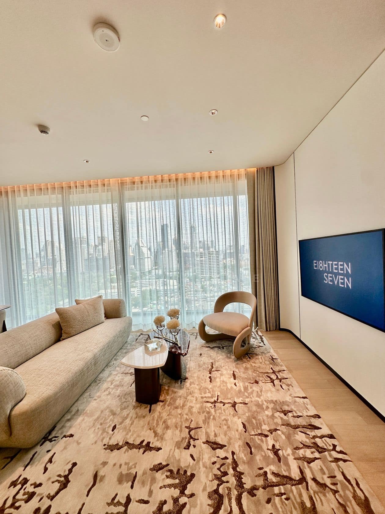 The living room of a two-bedroom residence at EI8HTEEN SEVEN, One Bangkok, facing the central Bangkok skyline